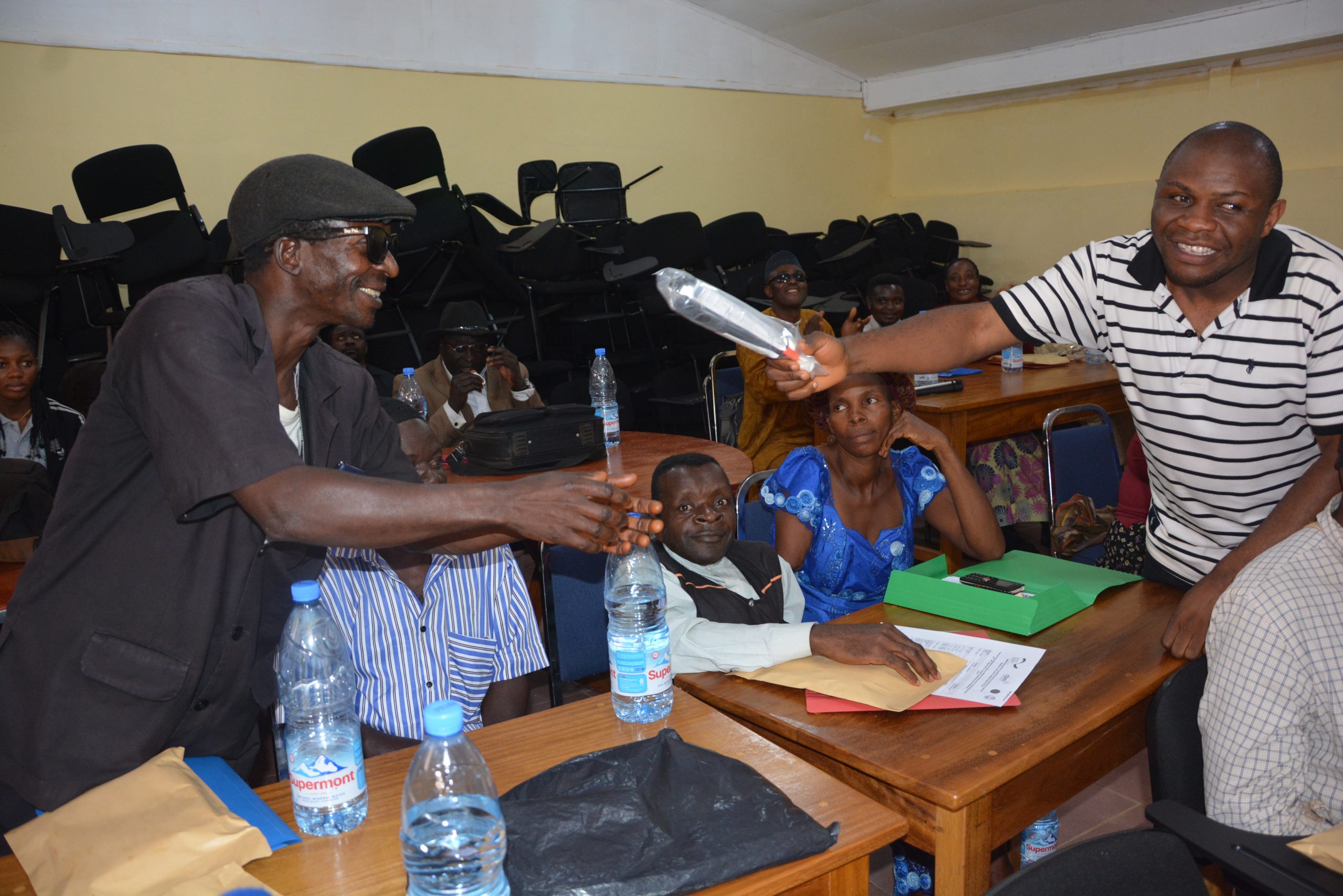 Ketchem Valentine receiving a new white cane from the Coordinator of CUAPWD