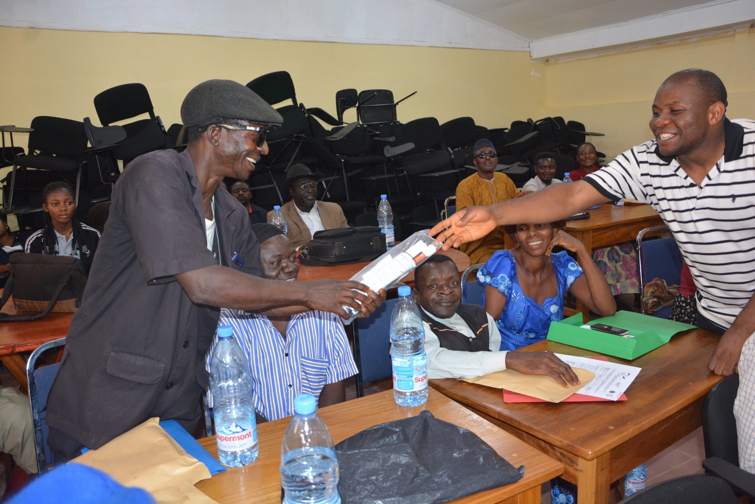 Ketchem Valentine receiving a new white cane from the Coordinator of CUAPWD